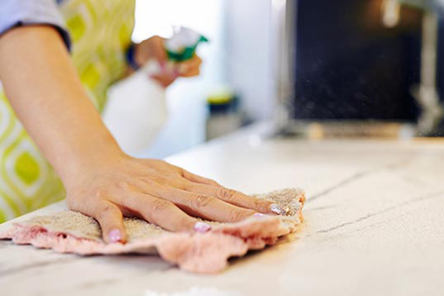 Hand wischt mit Mikrofasertuch über Tischplatte beim Reinigen, HappyMaids Basispaket professionelle Wohnungsreinigung