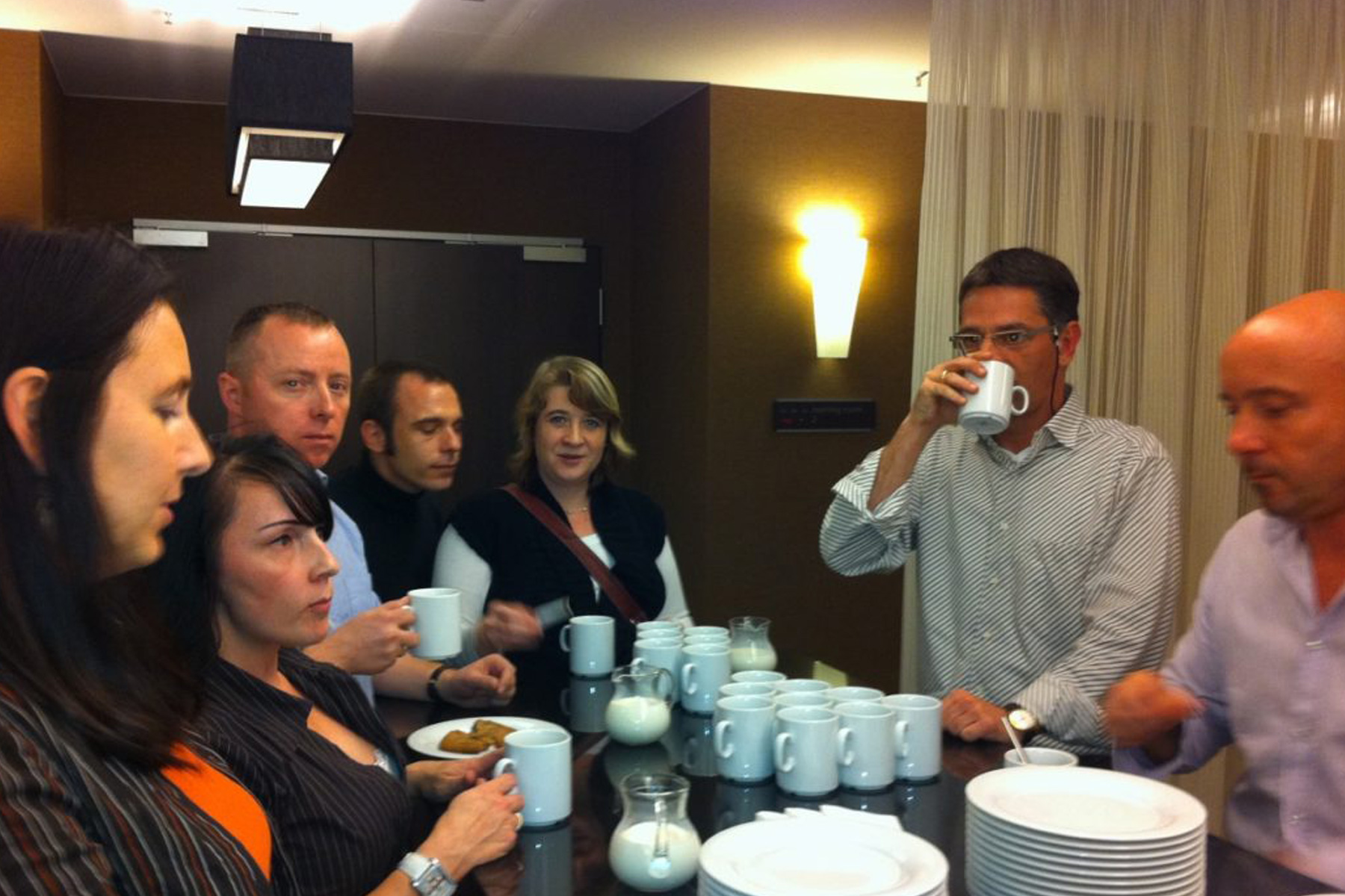 Gruppe von HappyMaids Franchisepartnern beim Partnertreffen in der Kaffeepause mit Tassen, Milchkännchen und Keksen