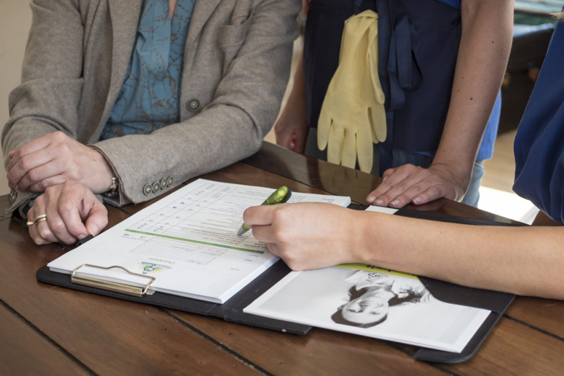 Hand unterschreibt Formular auf Klemmbrett während HappyMaids Franchisepartner in Schulung und Partnertreffen beraten