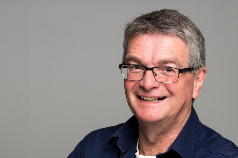 Porträt eines lächelnden Mannes mit Brille vor neutralem Hintergrund, HappyMaids Helmut Schmid