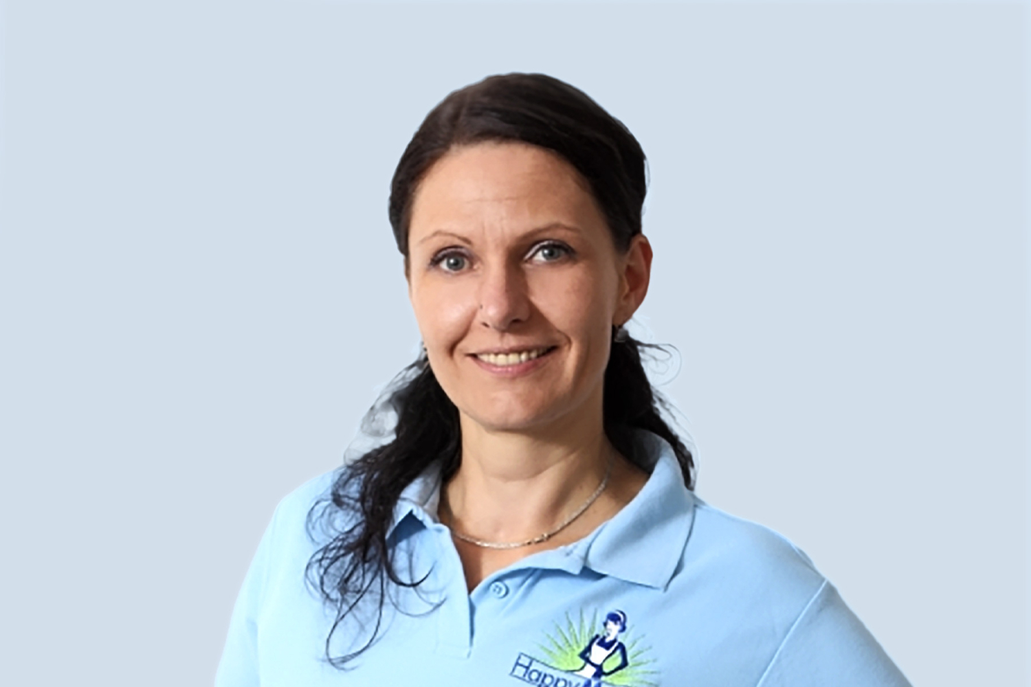 Porträt einer lächelnden HappyMaids Mitarbeiterin in hellblauem Poloshirt vor neutralem Hintergrund
