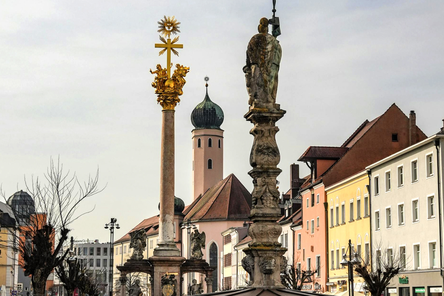 Stadtansicht Rosenheim mit Mariensäule, barocker Säule mit goldenem Kreuz und Turm der Kirche im Hintergrund