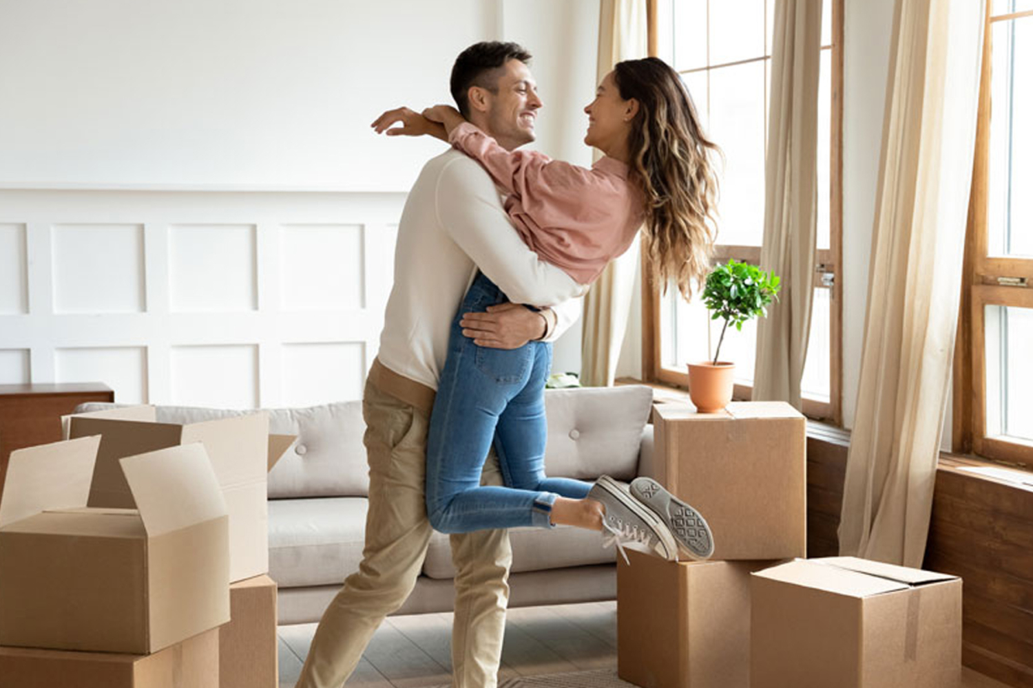 Paar freut sich beim Einzug in eine helle Wohnung zwischen Umzugskartons, Symbol für professionelle und gründliche Umzugsreinigung von HappyMaidS